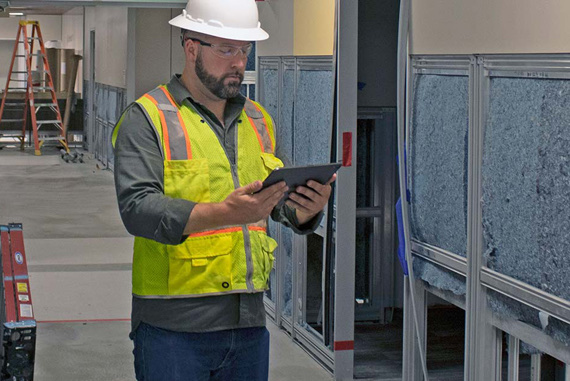 A construction worker uses a tablet to complete a job-site form.
